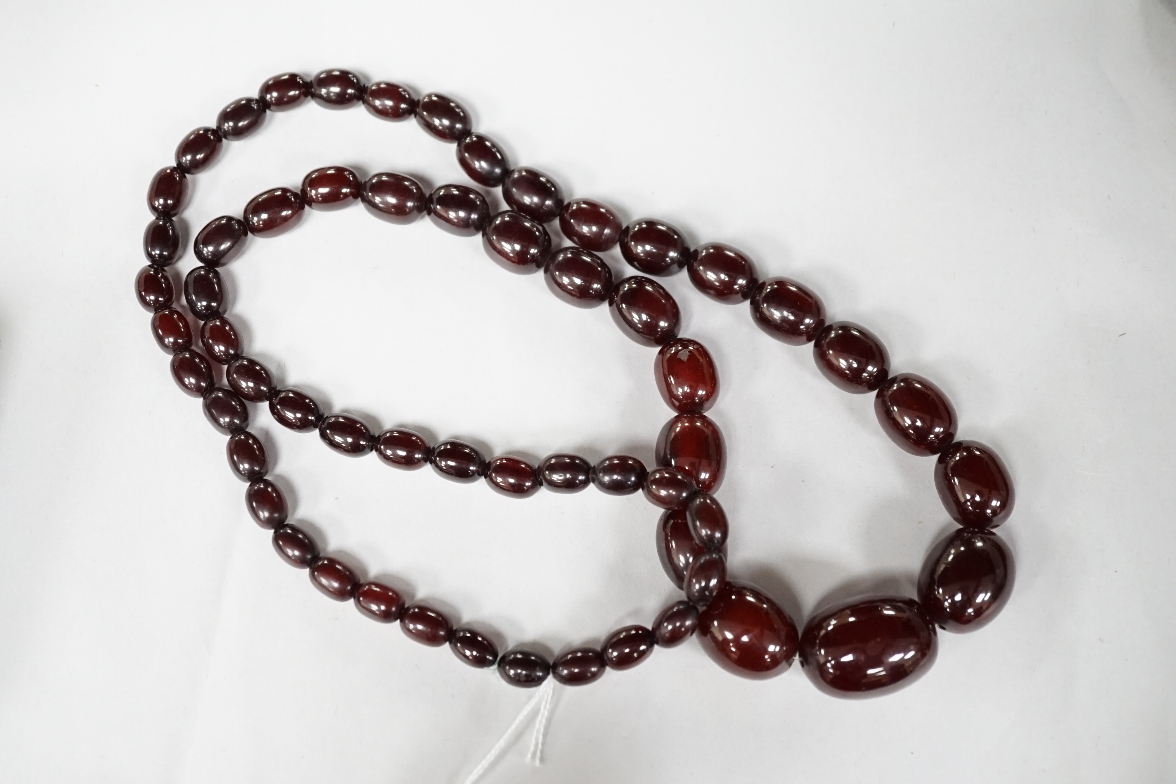 A single strand graduated simulated cherry amber oval bead necklace, 98cm, gross weight 140 grams. Condition - fair to good